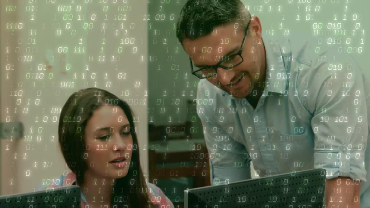 Insegnante che si china sulla scrivania, indicando il monitor e guidando uno studente che digita sulla tastiera per l'istruzione.