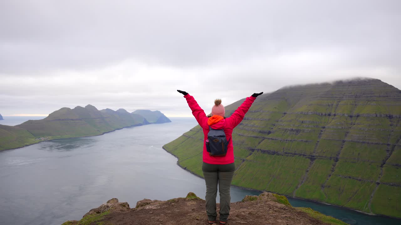 페로 제도 의 클라쿠르 산 꼭대기 에서 바다 를 바라보는 행복 한 여성 이 손 을 들고 있다