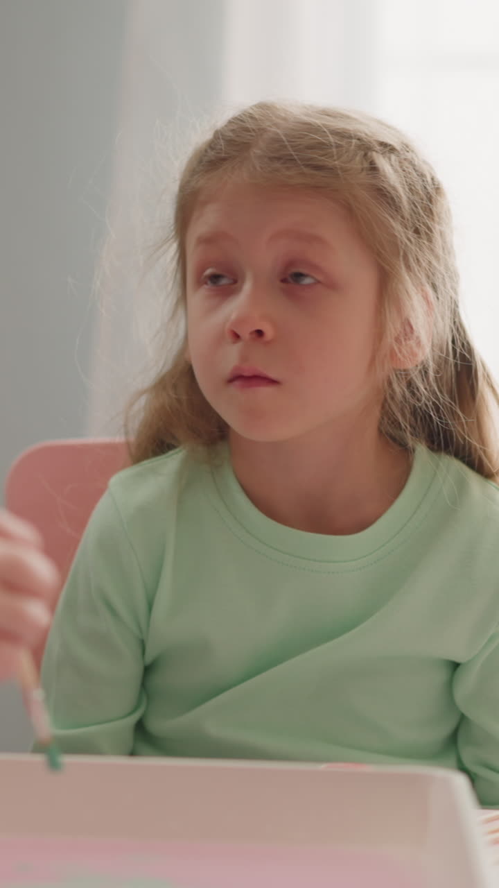 Bored little girl looks at elder sister dripping paint into water for Ebru art technique in studio closeup slow motion. Artistic hobby and education