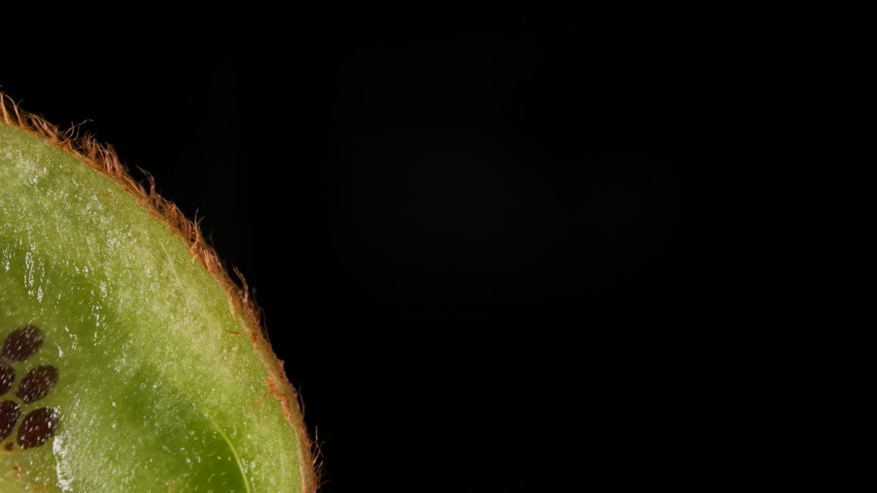 Macro Shot Slice of fresh Green Kiwi and Seeds Fruit on Black Background. Juicy Fresh Ripe Delicious Sliced Kiwi Fruit, Close-up.