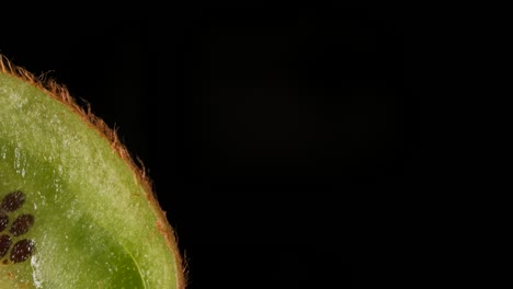 macro shot slice of fresh green kiwi and seeds fruit on black background. juicy fresh ripe delicious sliced kiwi fruit, close-up.