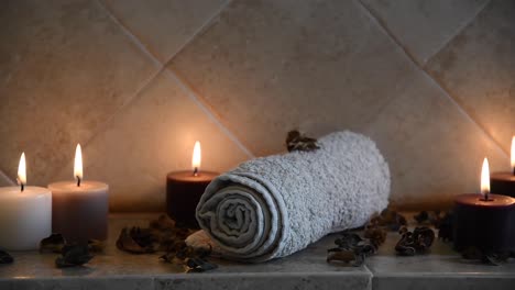 relaxing spa background with candles with flickering flames, some wooden petals and a towel