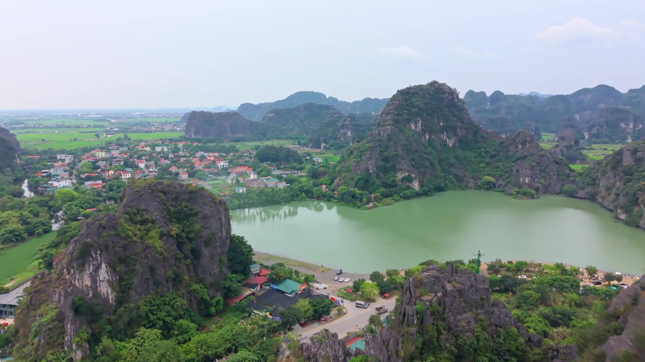 Cảnh quay drone cho thấy những ngọn núi đá vôi hiểm trở vươn lên xung quanh một hồ nước yên bình và phong cảnh nông thôn