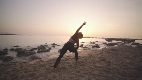 Mujer-Afro-Negra-Practicando-Yoga-Al-Amanecer-En-La-Playa-De-Arena,-Asana-Meditativa-De-Atención-Plena-Plantea-Ejercicios-Para-Una-Rutina-Matutina-Saludable