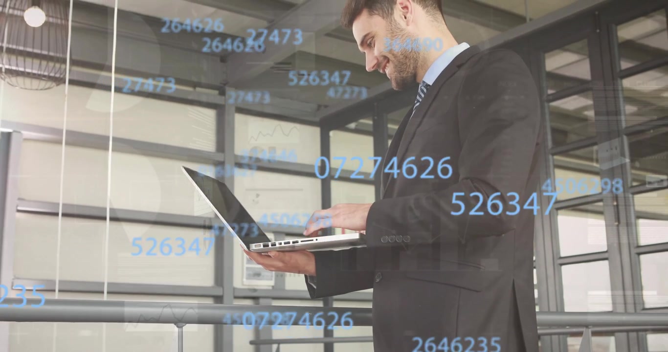 Profesional de negocios escribiendo en una laptop junto a la barandilla de un entresuelo, creando y analizando superposiciones de datos