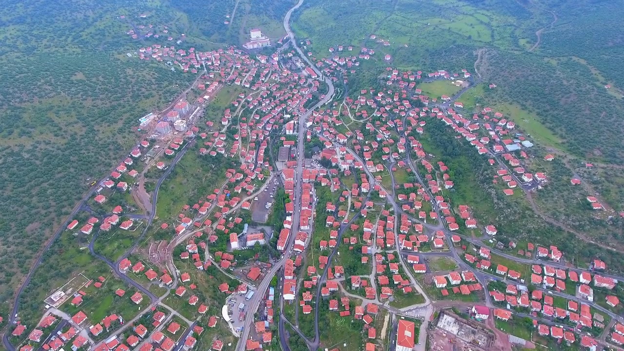 Aerial View of a Small Town Surrounded by Green Hills