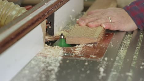 zooming in shot of a carpenter using an inverted router table in a carpenters workshop