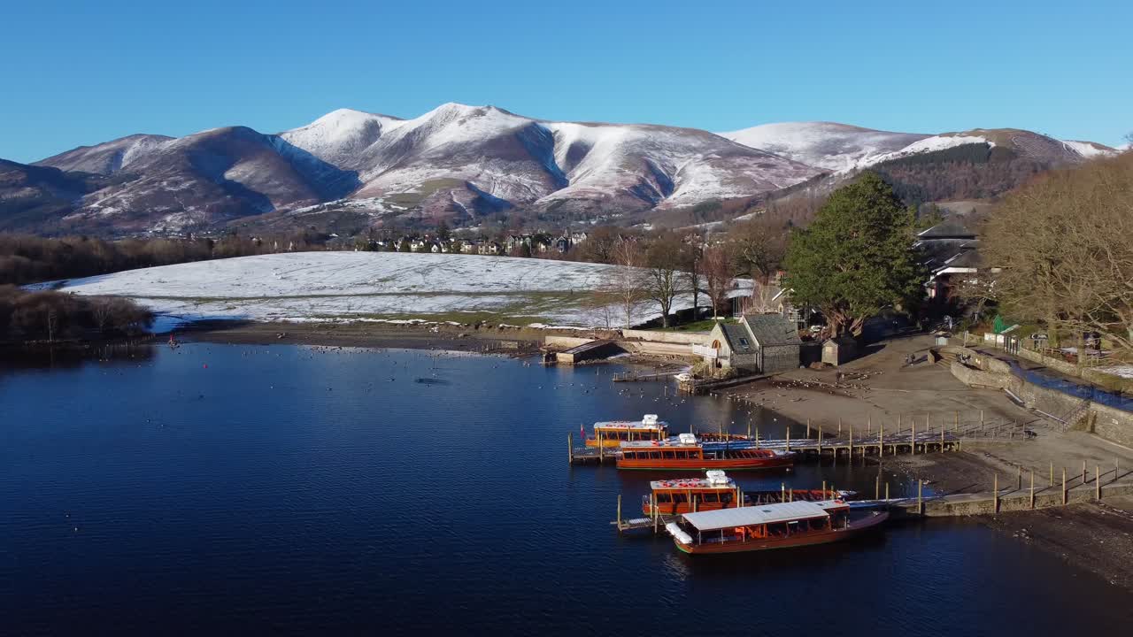 Cinematic drone view of Keswick by the lake, Derwentwater and snowy fells in the background