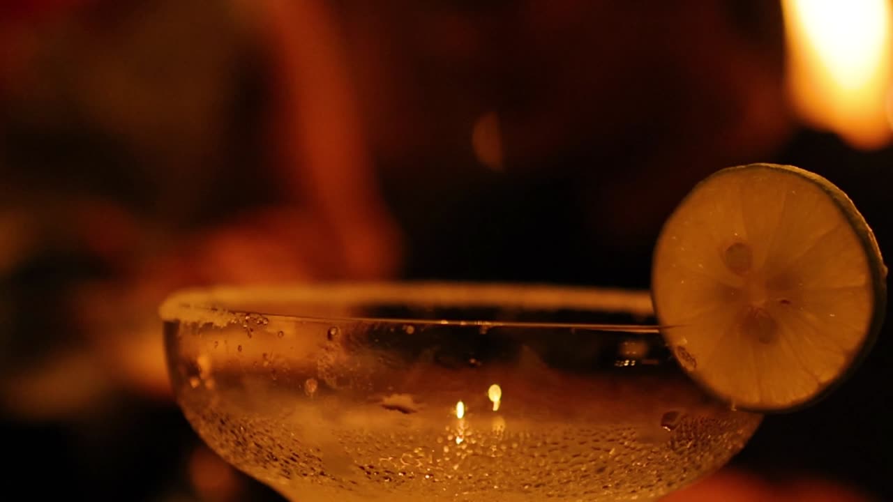 Primo piano di un bicchiere di margarita ghiacciato con una fetta di lime in un'illuminazione calda