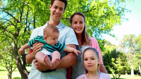familia joven saludando a la cámara en el parque