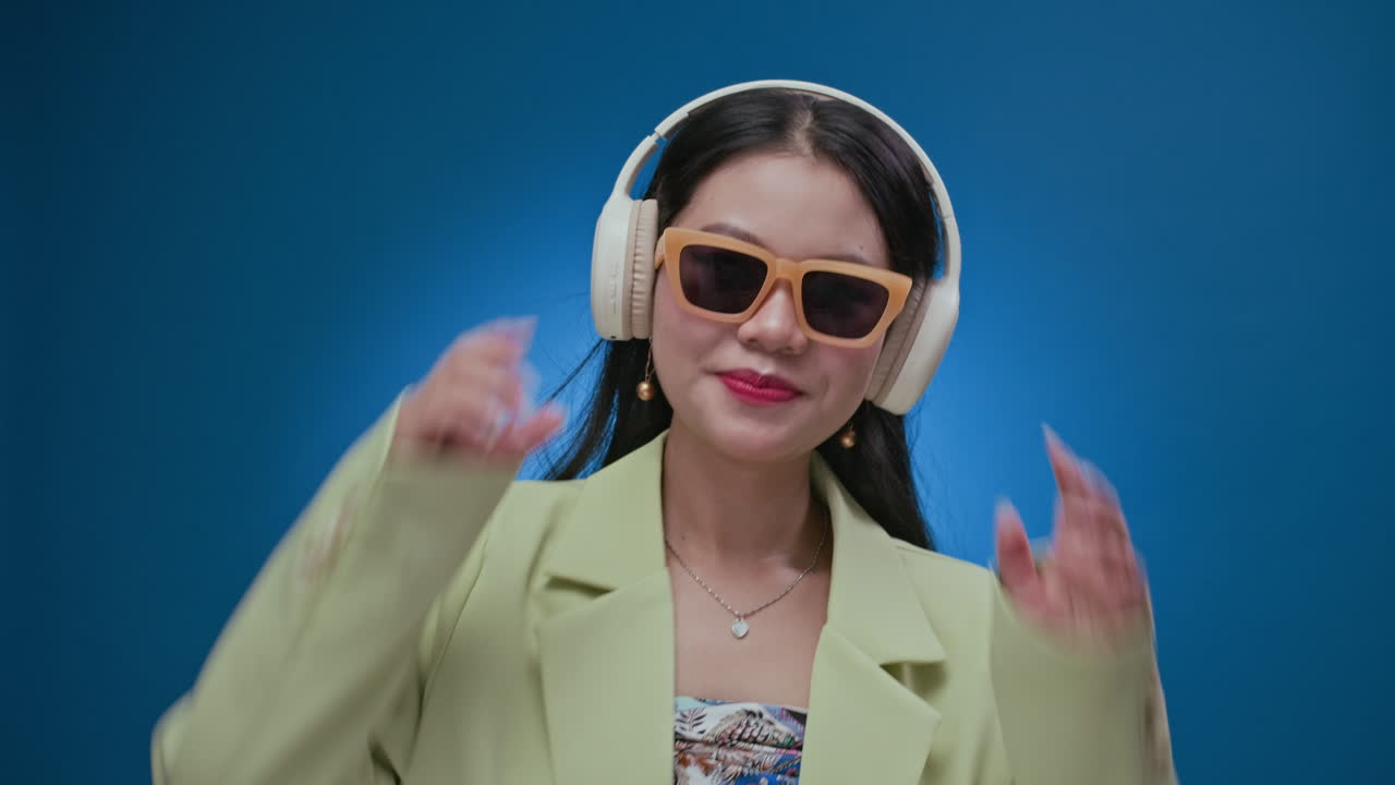 Female Zoomer in Sunglasses Dancing when Listening to Music in Headphones