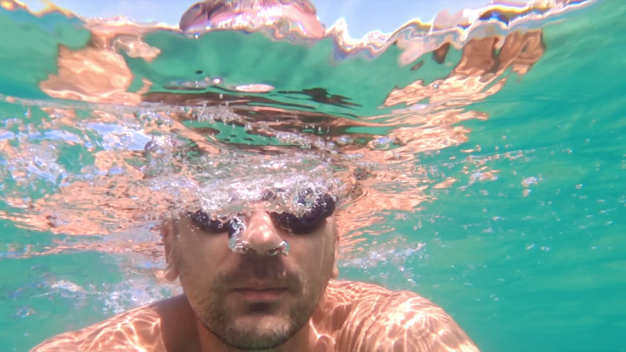 Man swimming underwater in the ocean with black goggles