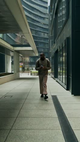 man walking in urban business district with coffee