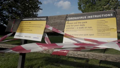 a park bench which has a coronvirus warning on it and lockdown tape in london