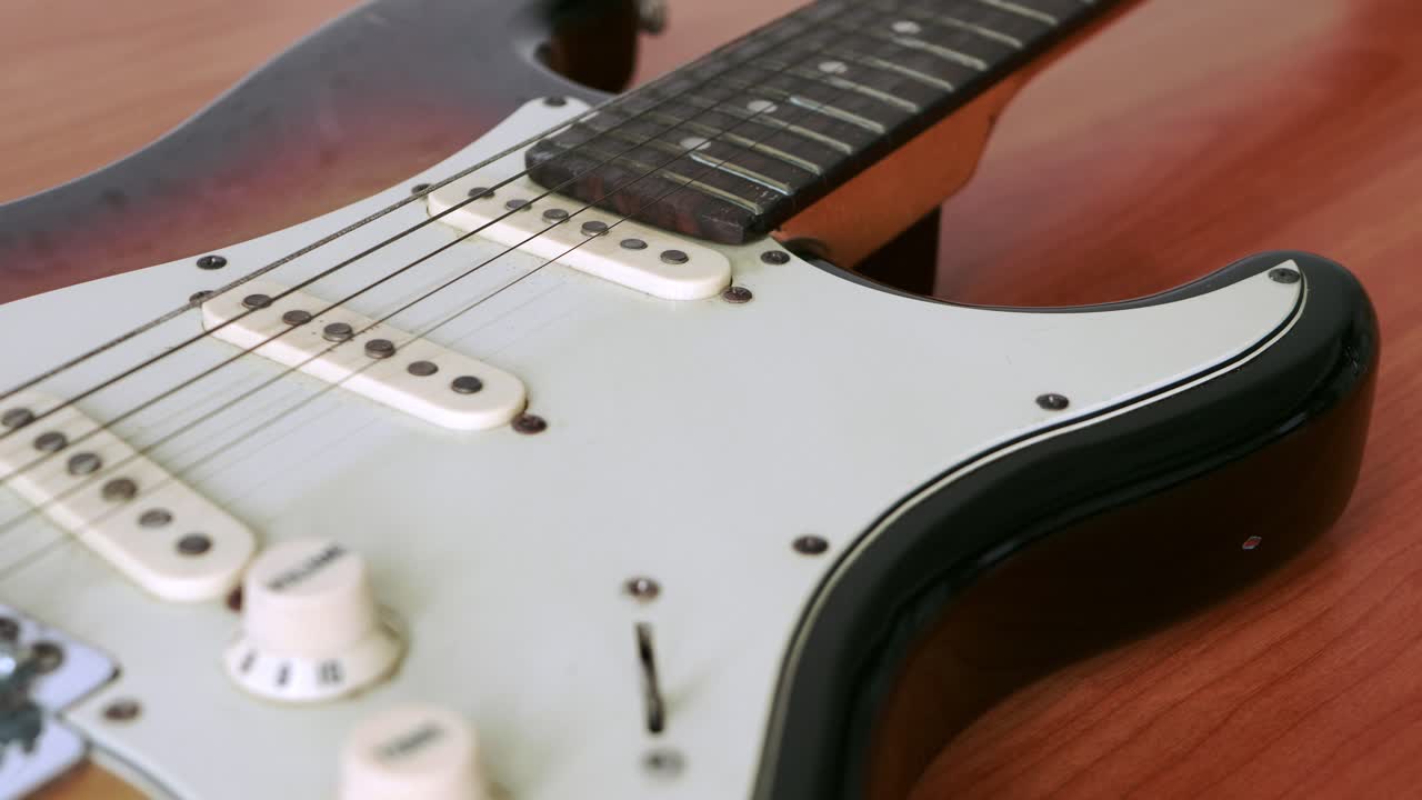 deslice el movimiento de la vieja guitarra eléctrica con un patrón fino de cuerdas de guitarra colocadas sobre una mesa de madera
