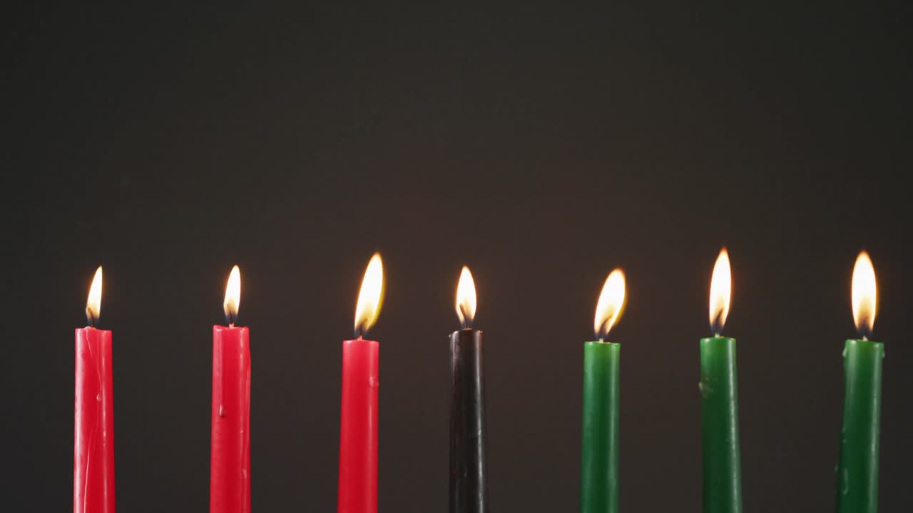 composición de velas verdes, negras y rojas encendidas de halloween contra un fondo negro