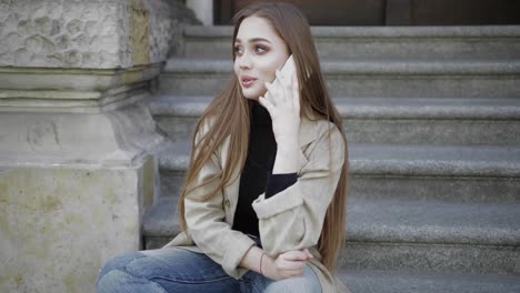 young stylish woman laughing and looking away while talking smartphone