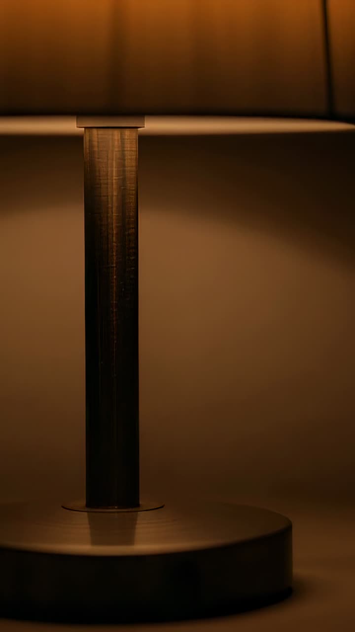 Camera lifting upward revealing lamp base and column, exposing pleated shade, warm glow for decor