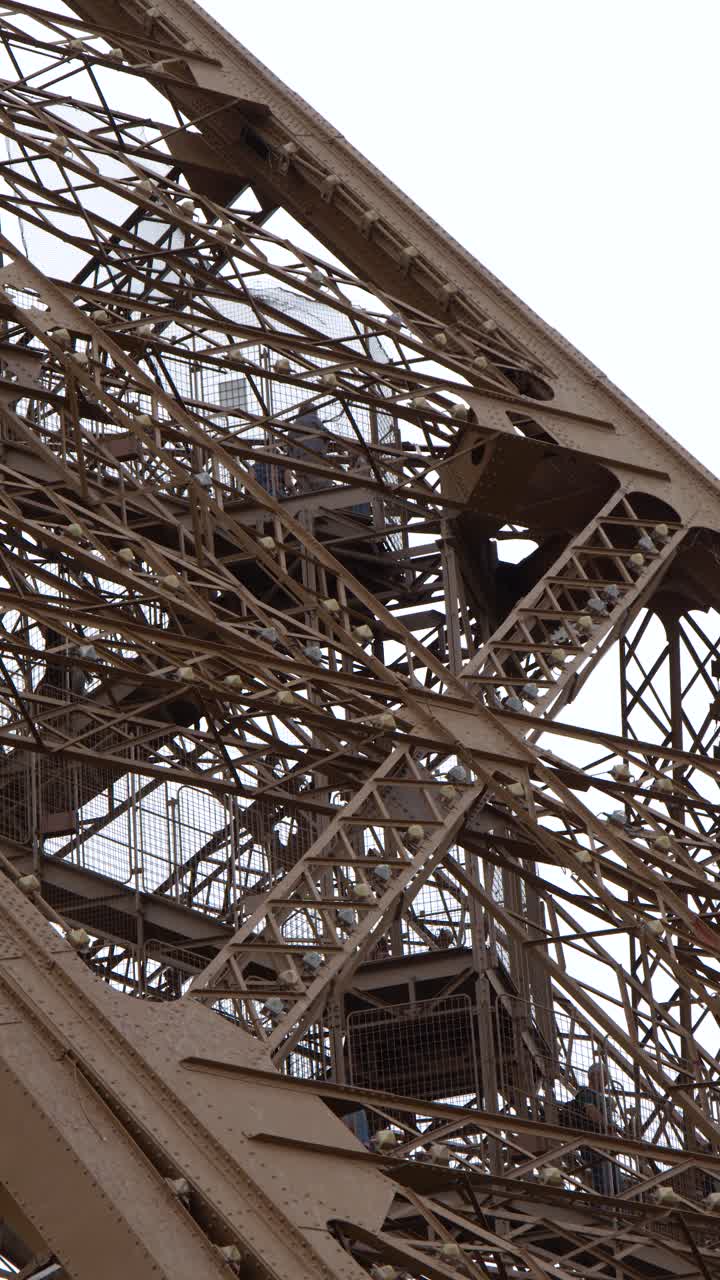 A detailed low angle shot of the brown iron beams and rivets against overcast sky