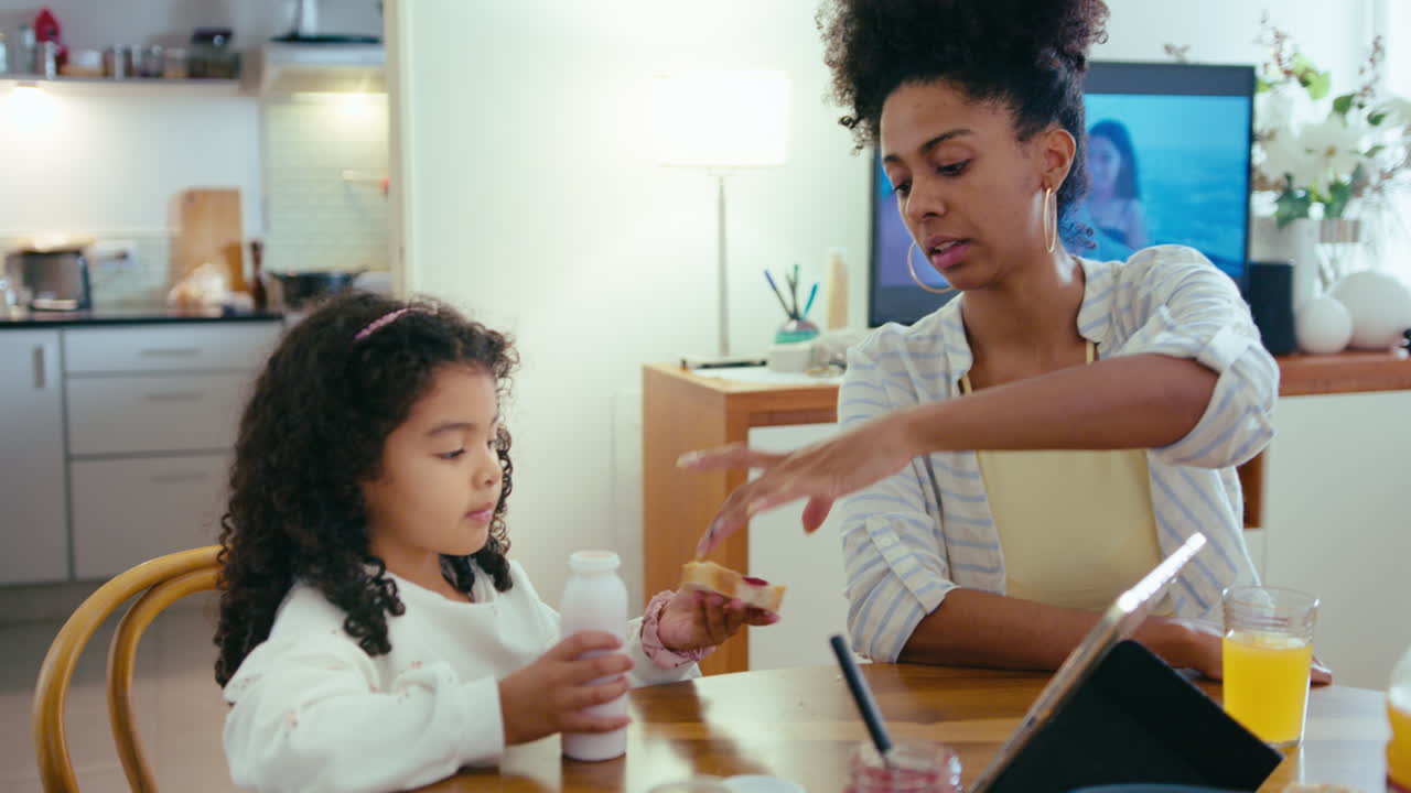 madre y hija afroamericanas desayunando en casa