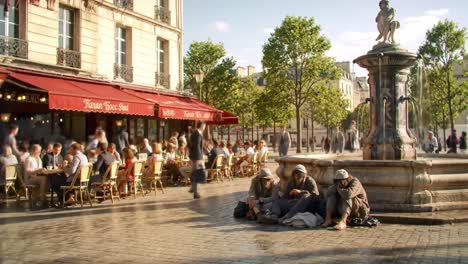 a lively street scene in paris featuring an outdoor cafe and fountain with people