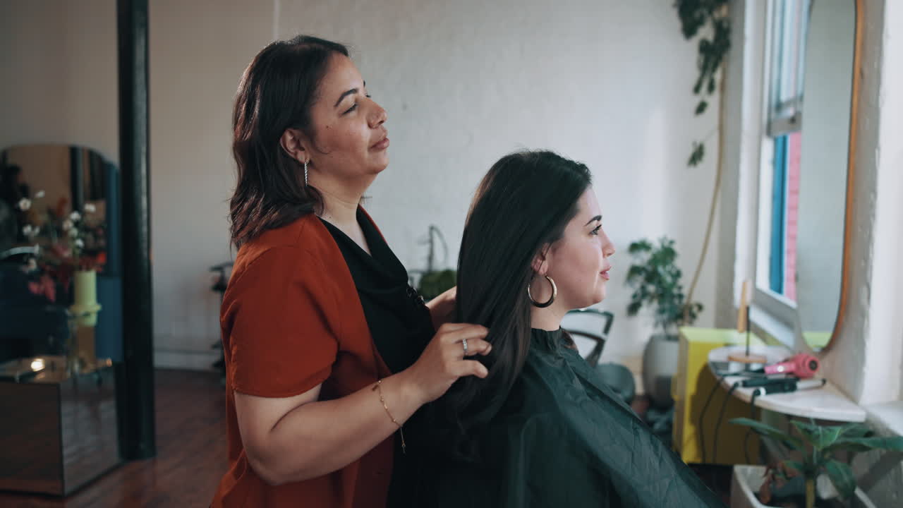 Hairstylist Combing and Styling Client's Hair in a Salon