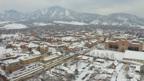 aerial drone panning shot of university of colorado boulder and mountains during snowy day - boulder,colorado,us