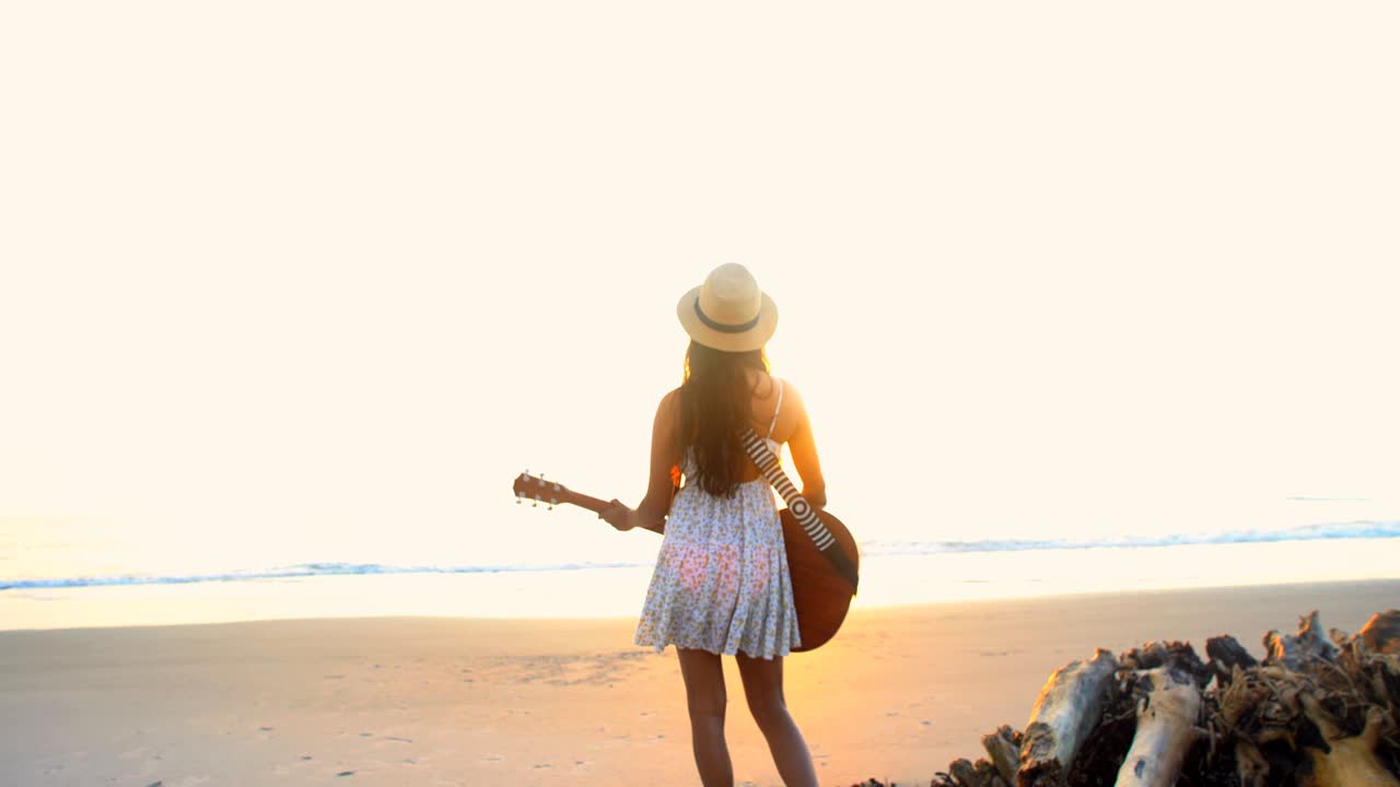 mujer india asiática en boho sundress tocando la guitarra