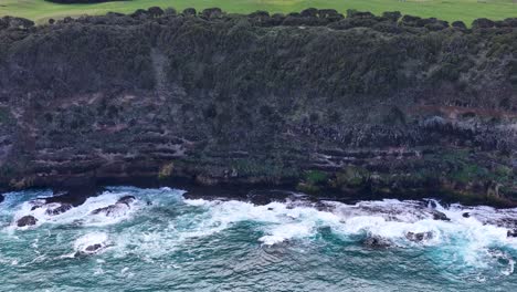 Drone captures rugged coastline, ocean waves, and rocky cliffs under natural daylight at Cape Schanck