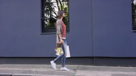 beautiful woman carrying shopping bags walking through city