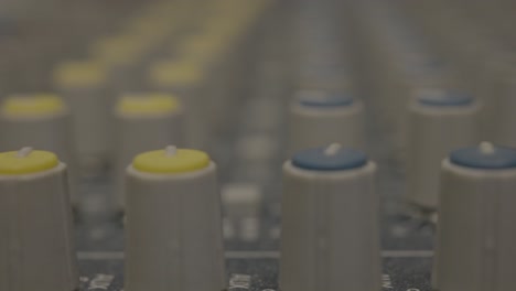 extreme close up of gray sound mixer knobs in a recording studio