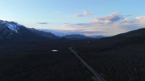 aerial establishing ascend of route 40 winding through the andes mountains in argentina, showcasing rugged snowcapped forested landscapes