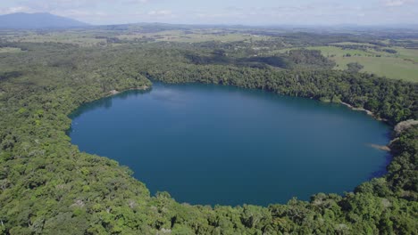 lush rainforests surrounding lake eacham in atherton tableland, queensland, australia - drone shot