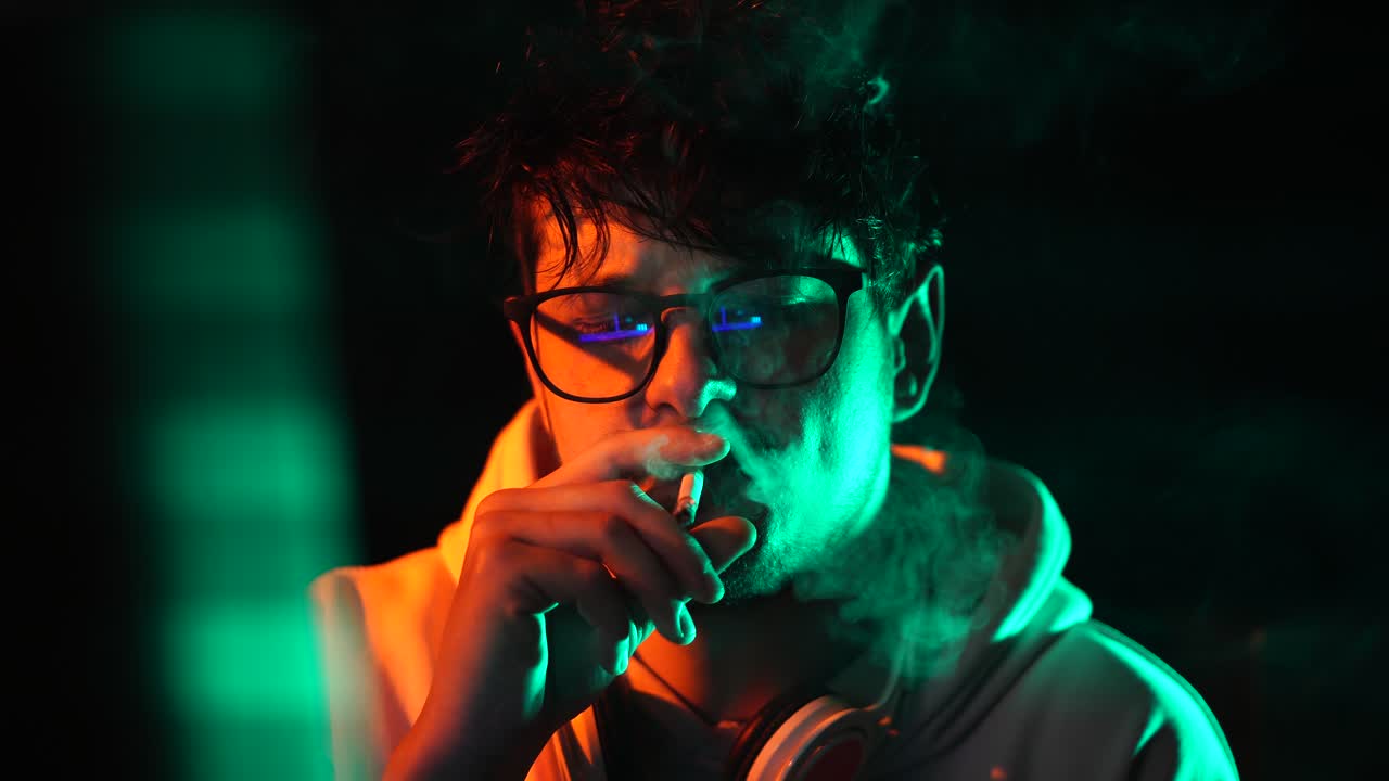 Computer Programmer or Hacker Smoking Cigarette in Front of Glitching Screen in Dark Room