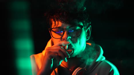 computer programmer or hacker smoking cigarette in front of glitching screen in dark room