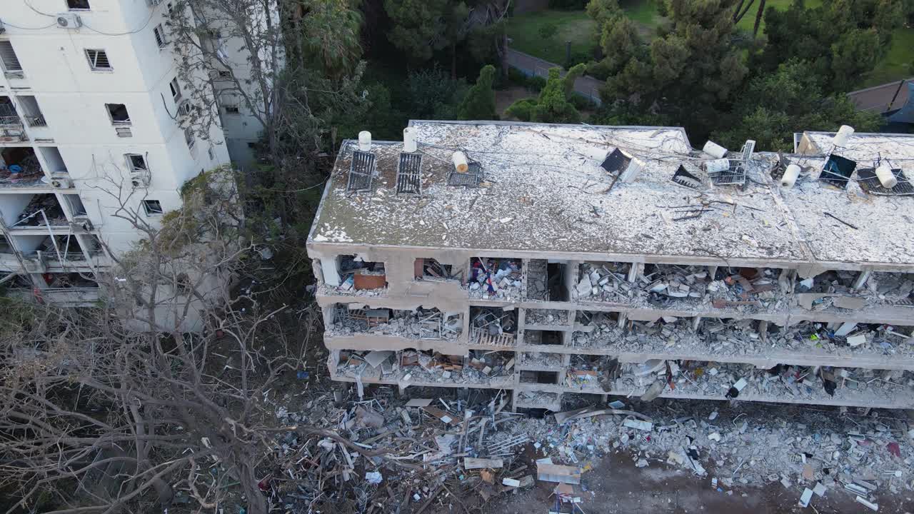 Low-altitude drone pans and rotates around a bombed residential building in Tel Aviv.