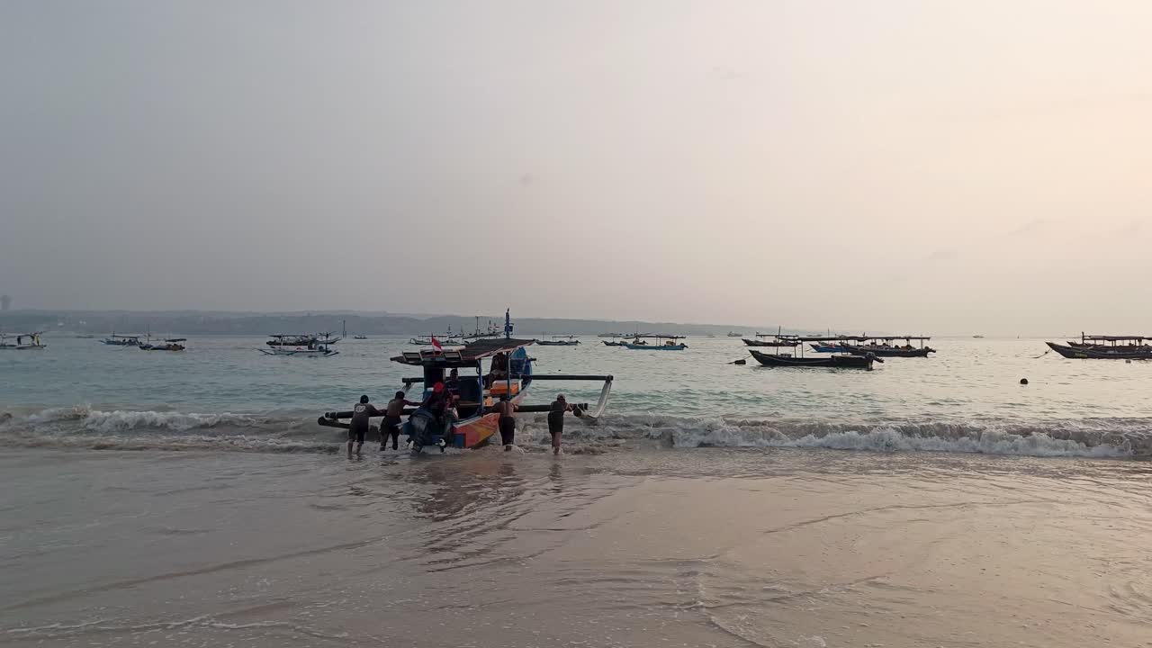 Fishermen Pulling Boat on Beach at Sunset in Bali