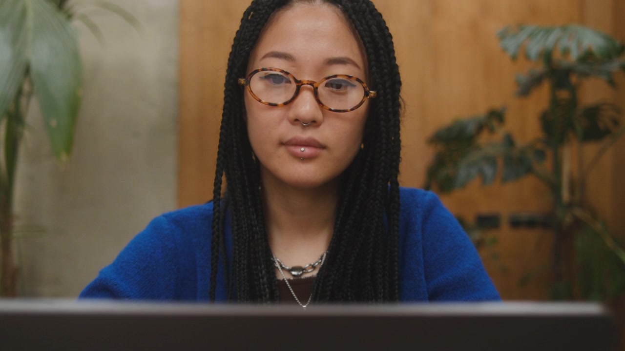 Concentrated Young Asian Woman Working on Laptop in Creative Office