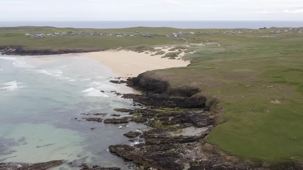 Drone shot of the rocks around Eoropie beach in Ness and the coastline beyond it on a sunny, Summer's day