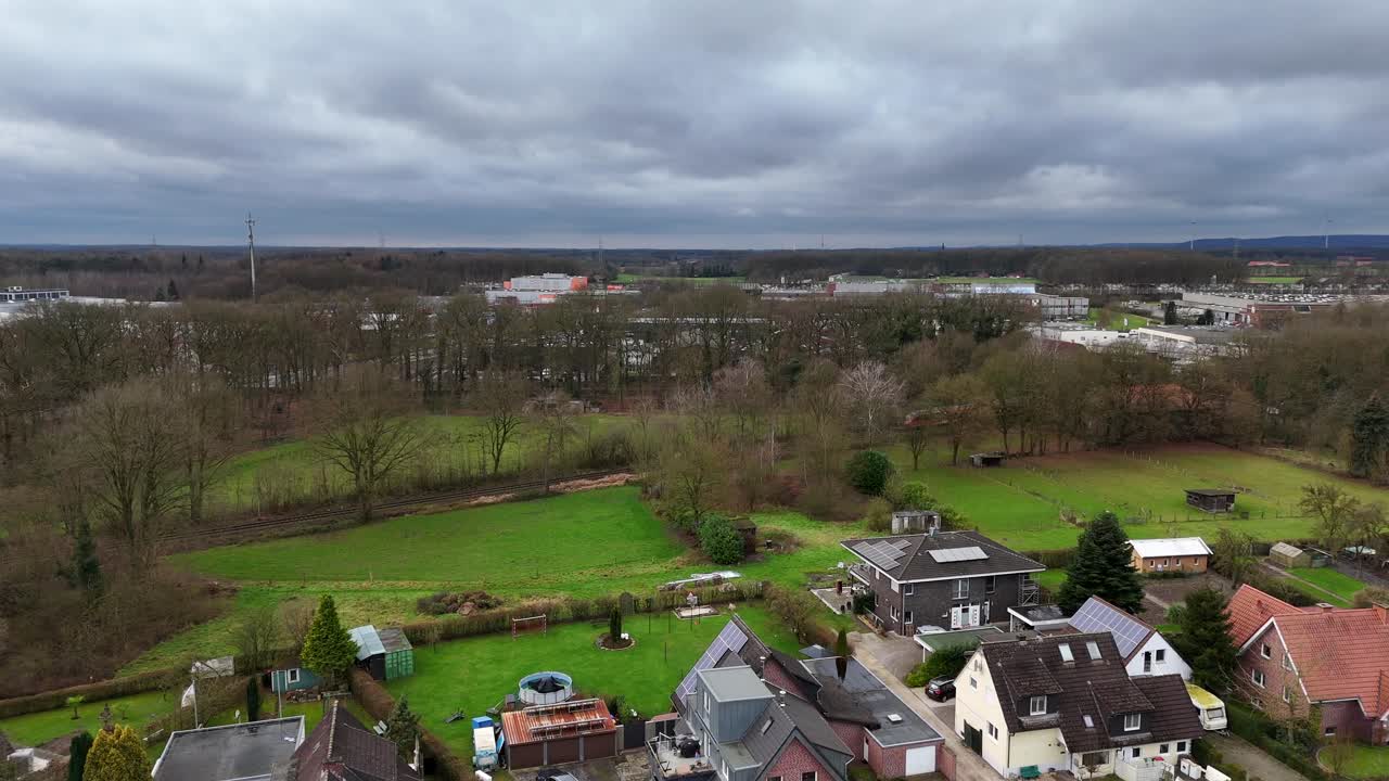 Aerial establishing shot of train on rail during autumn season with cloudy sky. Housing area with villas and single family homes in USA. Scenic suburb landscape of Germany.