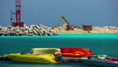 timelapse of heavy machinery working across the bay with turquoise water