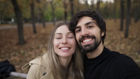 pareja de amor haciendo una selfie en un banco en el parque en la temporada de otoño