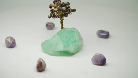 Beautiful-Crystal-Wire-Tree-Standing-On-The-Green-Amethyst-Surrounded-By-Five-Purple-Gem-Stones---Close-Up-Shot