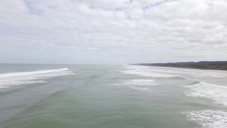 Slowmotion aerial shot of waves crashing onto the black sand Muriwai beach, New Zealand