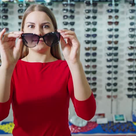 portrait of smiling young woman holds new sunglasses. stylish black eyewear in the hands of a beautiful girl at optical store.