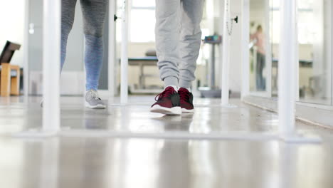 walking on parallel bars, person in rehabilitation with therapist in gym
