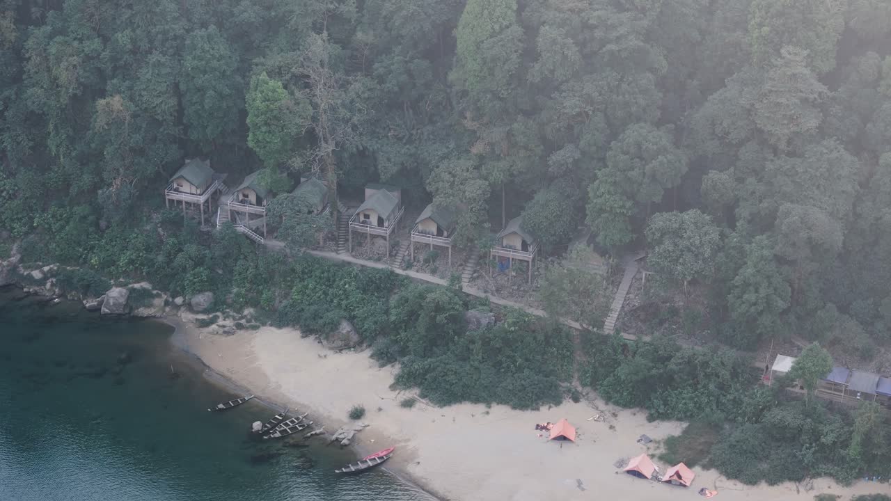 Aerial view of riverside campsites and stilted cabins on the banks of the Umngot River in Shnongpdeng, Meghalaya