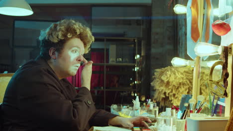 hombre haciendo maquillaje de payaso en el camerino