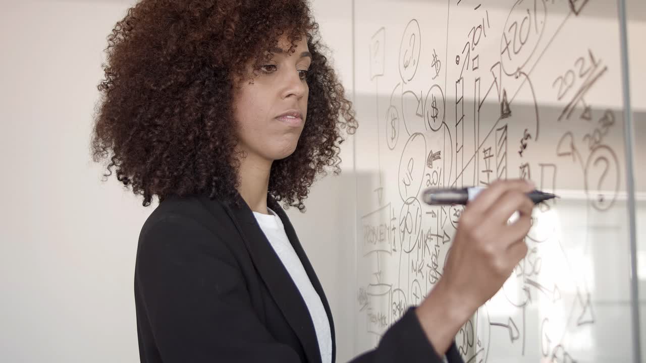 Serious young African American manager drawing infographics