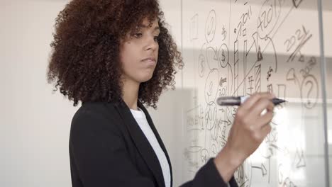 joven gerente afroamericano serio dibujando infografías